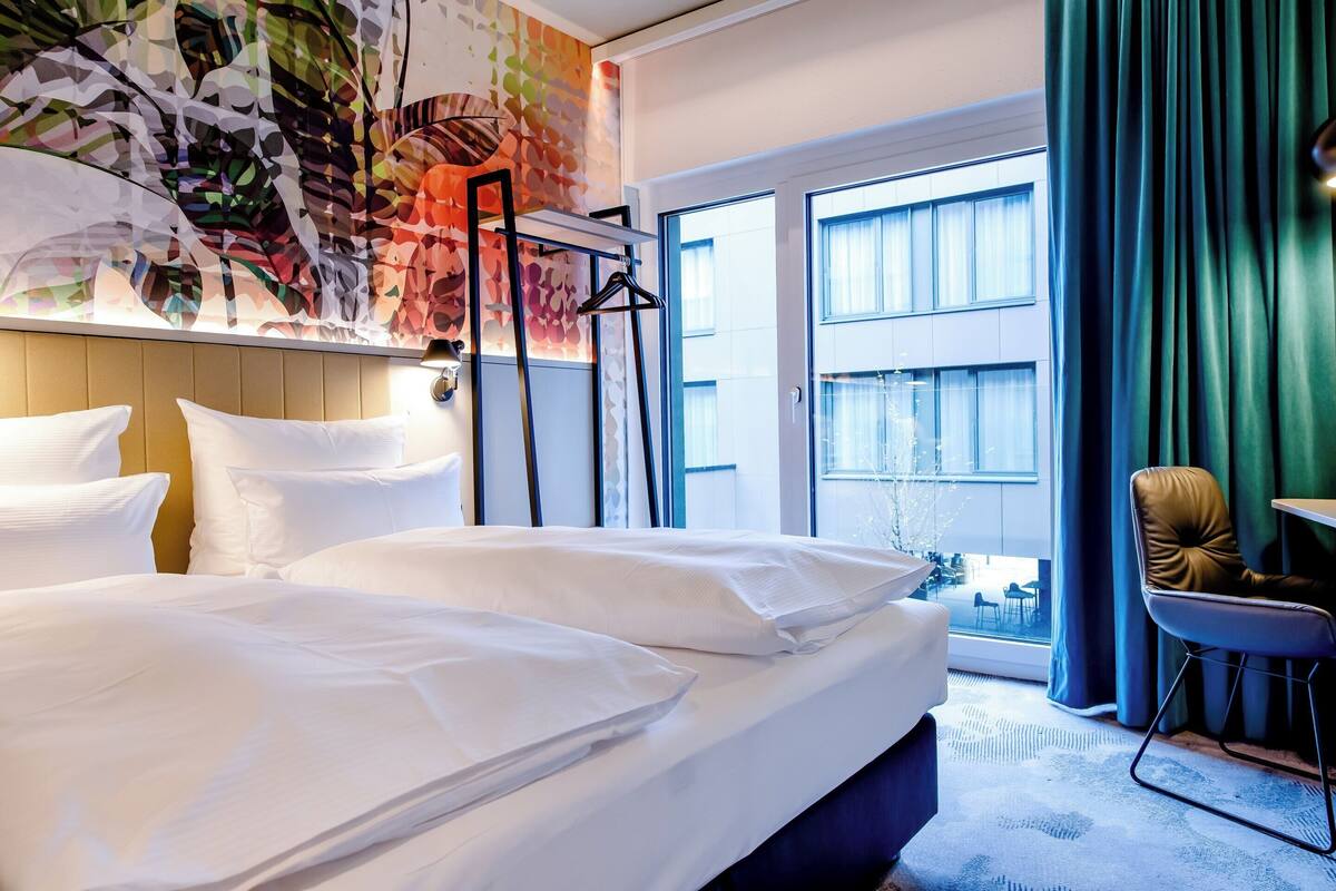 Une chambre d’hôtel avec un grand lit, un bureau, une chaise et une vue sur l’extérieur.