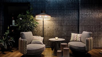 Ein gemütlicher Sitzbereich mit zwei Sesseln, einem kleinen Tisch, einer Stehlampe und einem Blumentopf.