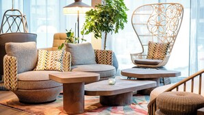Un salon moderne avec un canapé, des fauteuils, une table basse et un fauteuil suspendu.