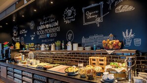 Un buffet de petit-déjeuner proposant une variété d’aliments, des machines à café et des tasses.