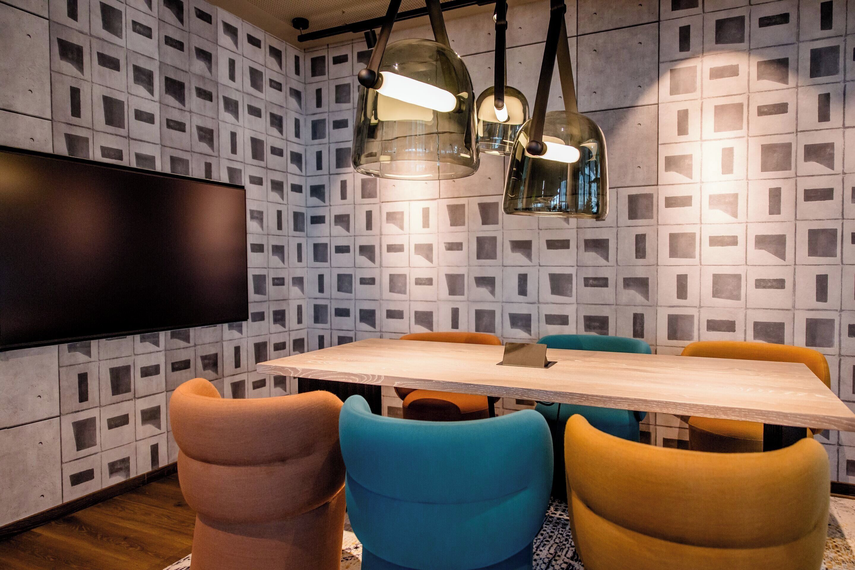 Een moderne eetruimte met een houten tafel, kleurrijke stoelen en hanglampen.