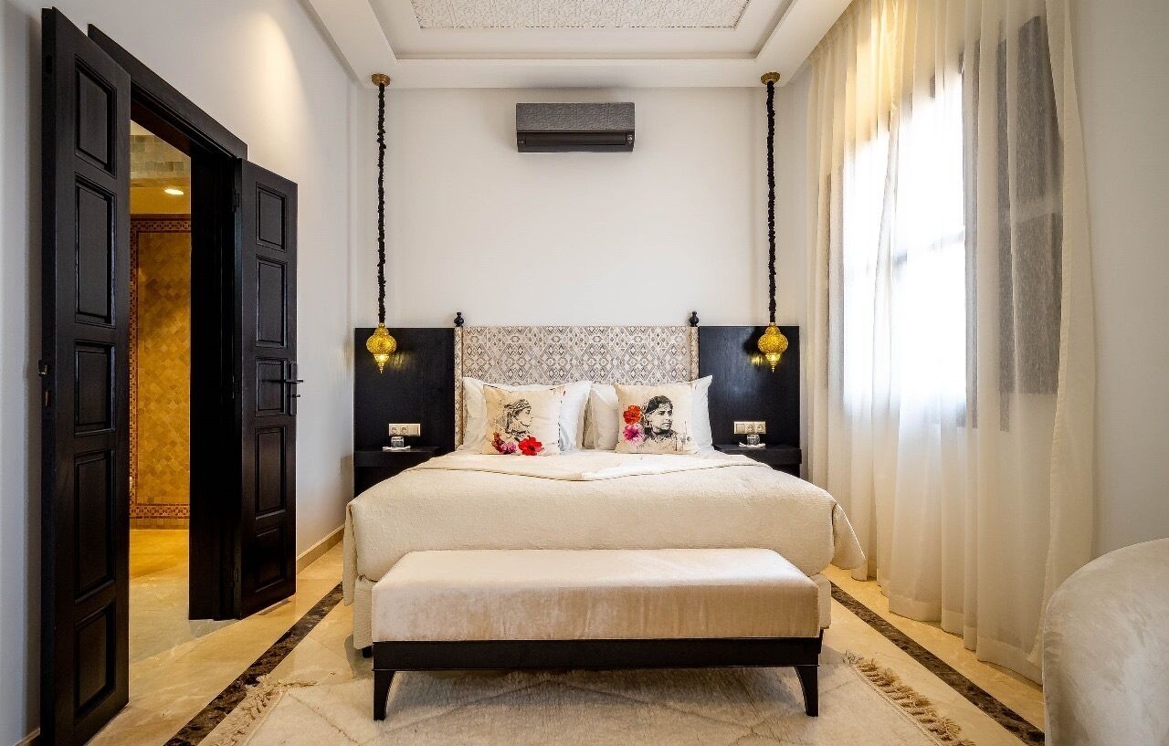 A bedroom with a large bed, bedside tables, a bench, and a ceiling fan.