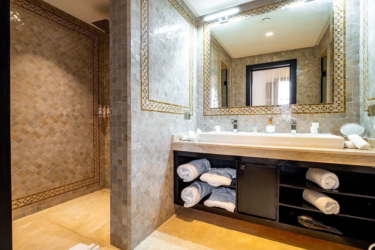 A bathroom with a large mirror, a sink, and a towel rack.