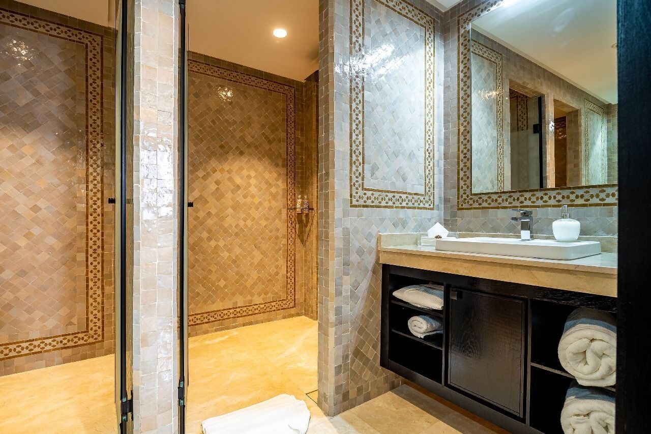 Un baño moderno con cabina de ducha de vidrio, lavamanos con espejo y toallero.