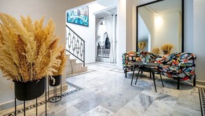 Un interior moderno con una escalera, un conjunto de sofás coloridos y plantas decorativas.