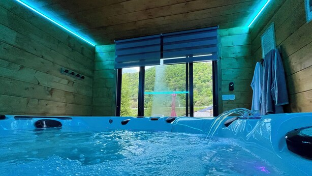 A hot tub with a view of a forest through a large window.
