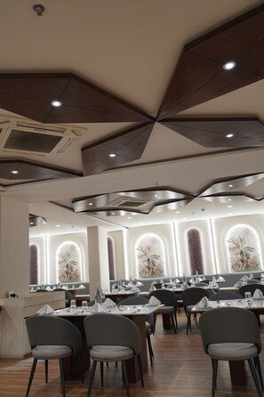 Un restaurant dotĂ© dâun plafond au design moderne, de plusieurs tables et de chaises.