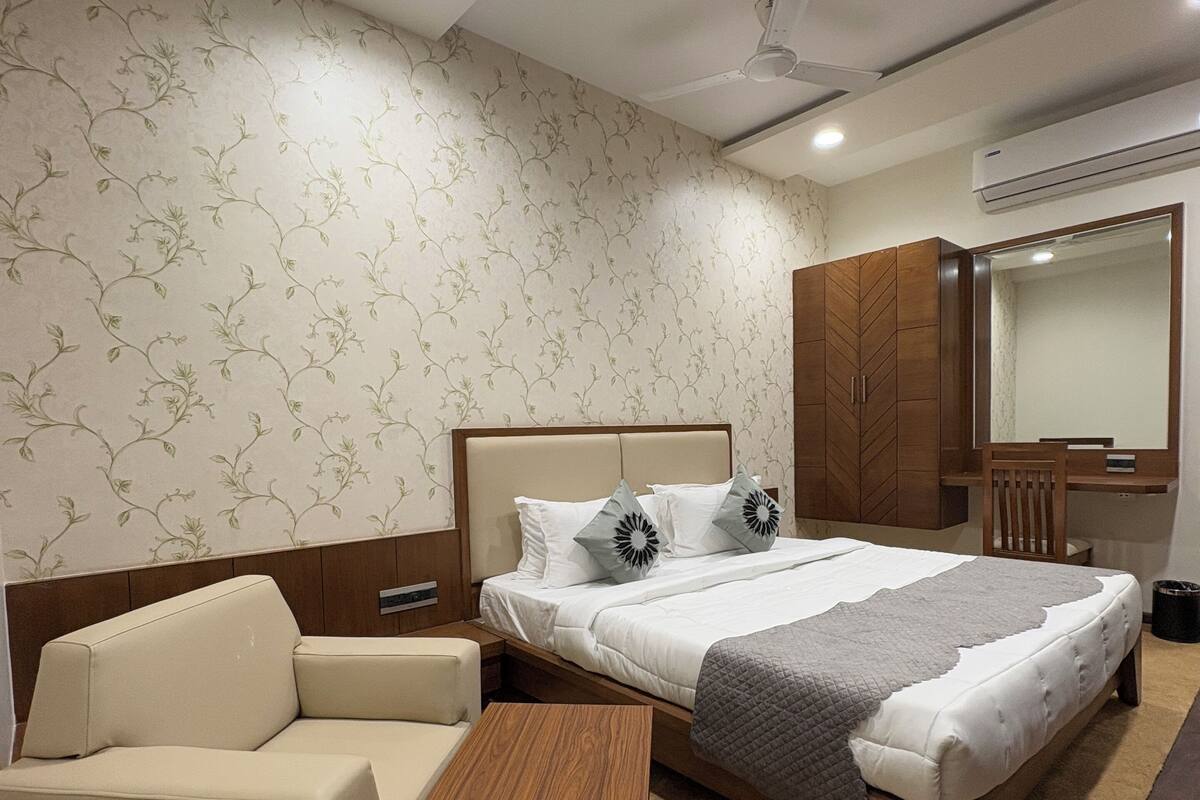 Een hotelkamer met een bed, een slaapbank, een houten salontafel en een kledingkast.