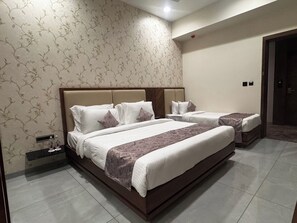 Une chambre dâhĂŽtel avec un grand lit, une table de chevet avec une bouteille et une commode.