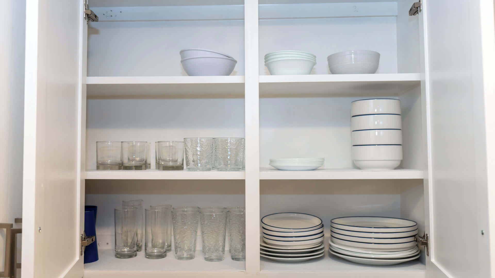 Un meuble blanc avec des étagères contenant des bols, des assiettes et des verres.