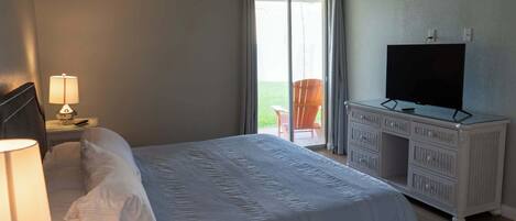 A hotel room with a bed, a television on a dresser, and a window with curtains.