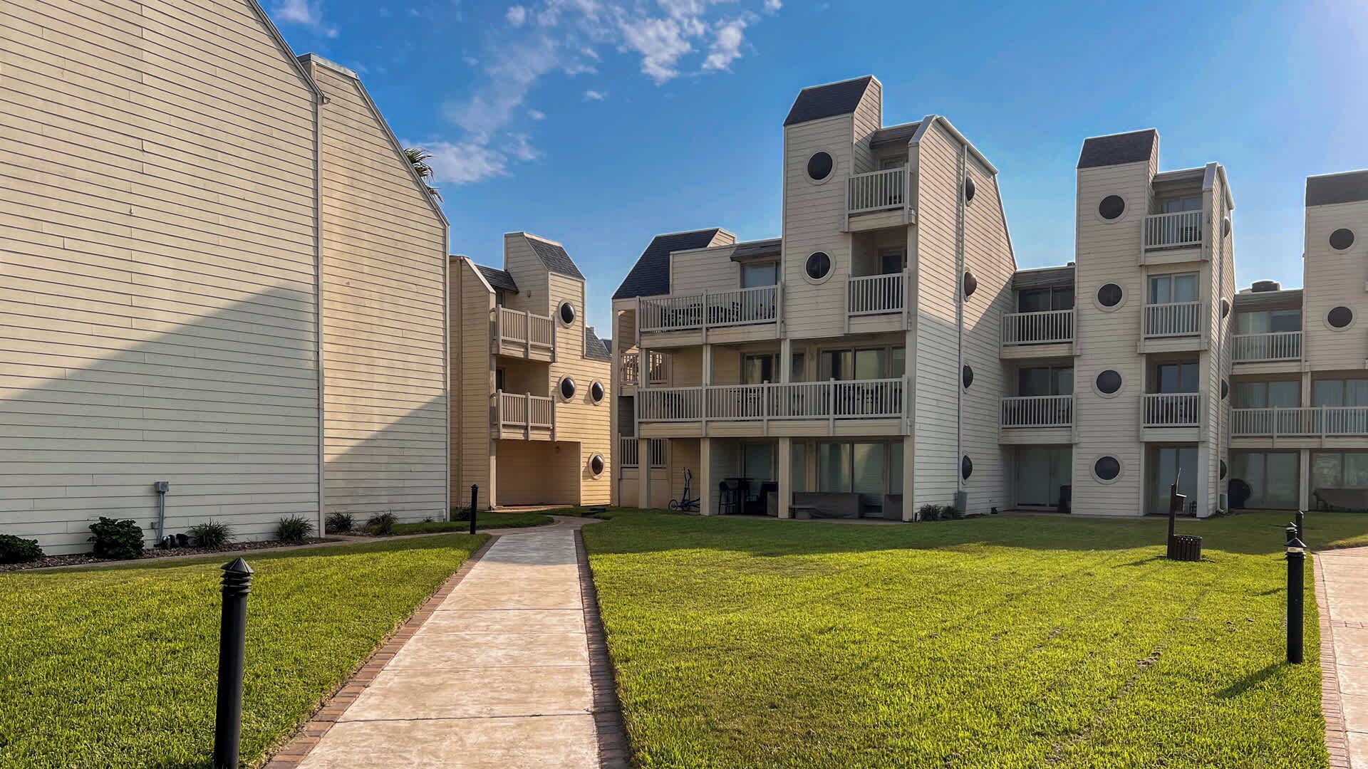 Un complesso residenziale moderno con cortile interno, numerosi balconi e prato curato.
