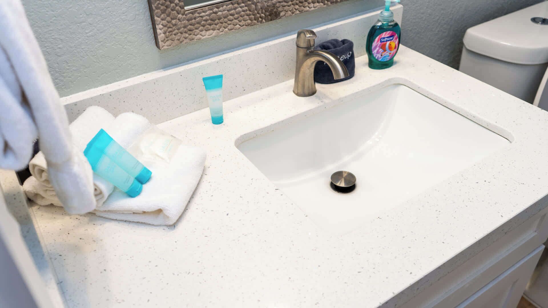 A bathroom sink with a faucet, a soap dispenser, and a towel.