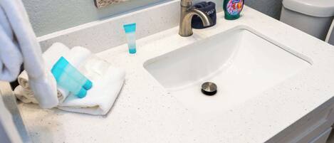 A bathroom sink with a faucet, a soap dispenser, and a towel.