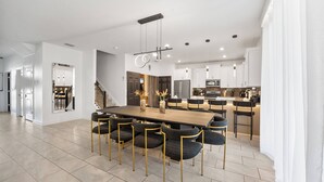 Una cocina moderna con una isla central, electrodomésticos de acero inoxidable e iluminación colgante.