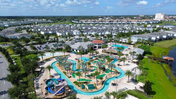 Un resort con una piscina grande, un tobogán acuático y un campo de golf.