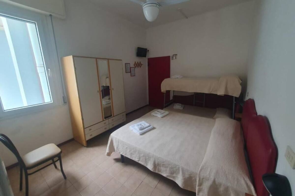 A bedroom with a bed, a chair, a wardrobe, and a ceiling fan.