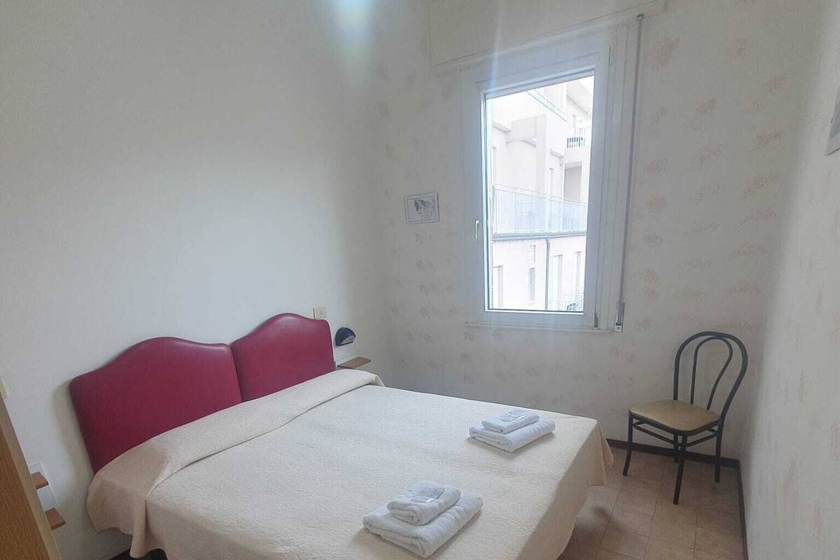 A bedroom with a bed, a chair, a window, and a door.