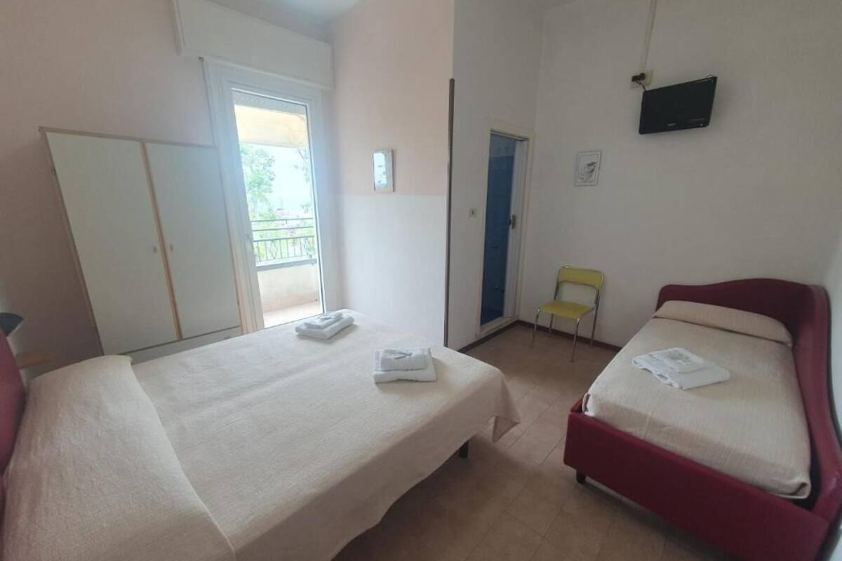 A room with two beds, a TV, and a balcony.