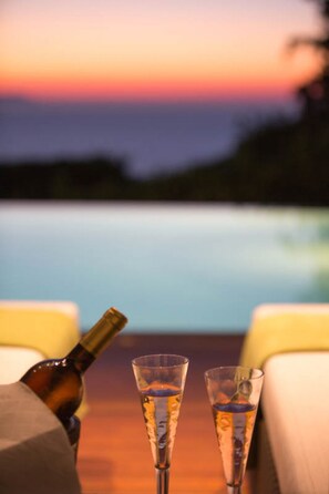 A sunset view with two glasses of a beverage and a bottle on a table. - Villa Terra Creta Luxury Retreat and Spa (Chania)