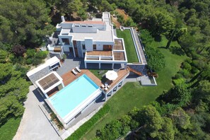 Une maison moderne dotée d’une grande piscine, d’une terrasse et d’une pelouse bien entretenue.