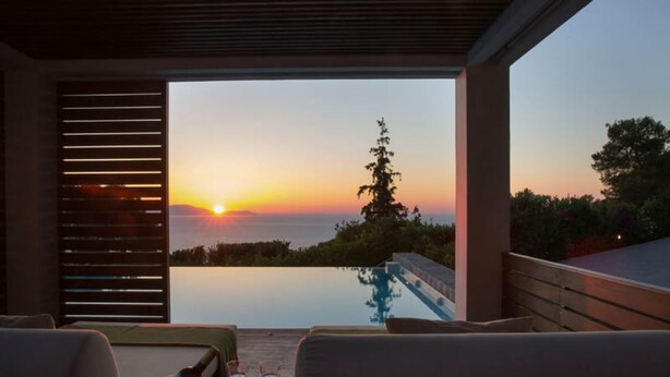A sunset view from a covered outdoor seating area with a pool. - Villa Terra Creta Luxury Retreat and Spa (Chania)