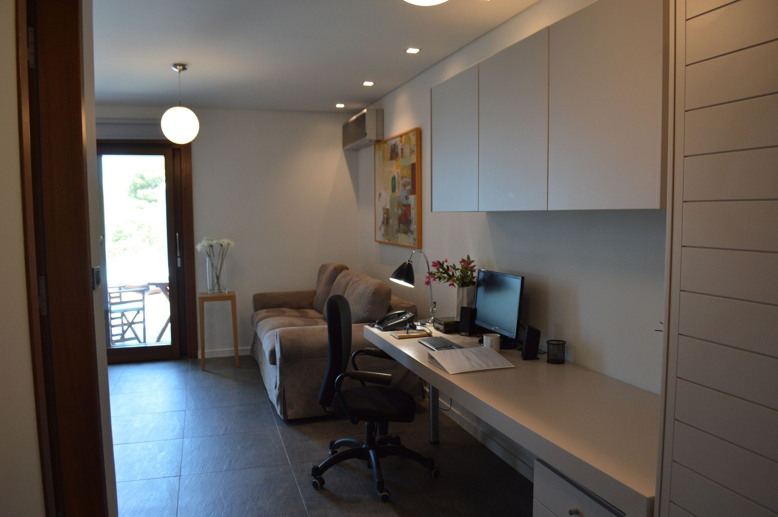 Um espaço de escritório moderno com uma mesa, cadeira, computador e um quadro na parede.