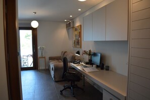 Ein moderner Büroraum mit Schreibtisch, Stuhl, Computer und einem Bild an der Wand.