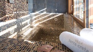 A modern bathroom with mosaic tile walls, a large bathtub, and a window providing natural light. - Villa Terra Creta Luxury Retreat and Spa (Chania)