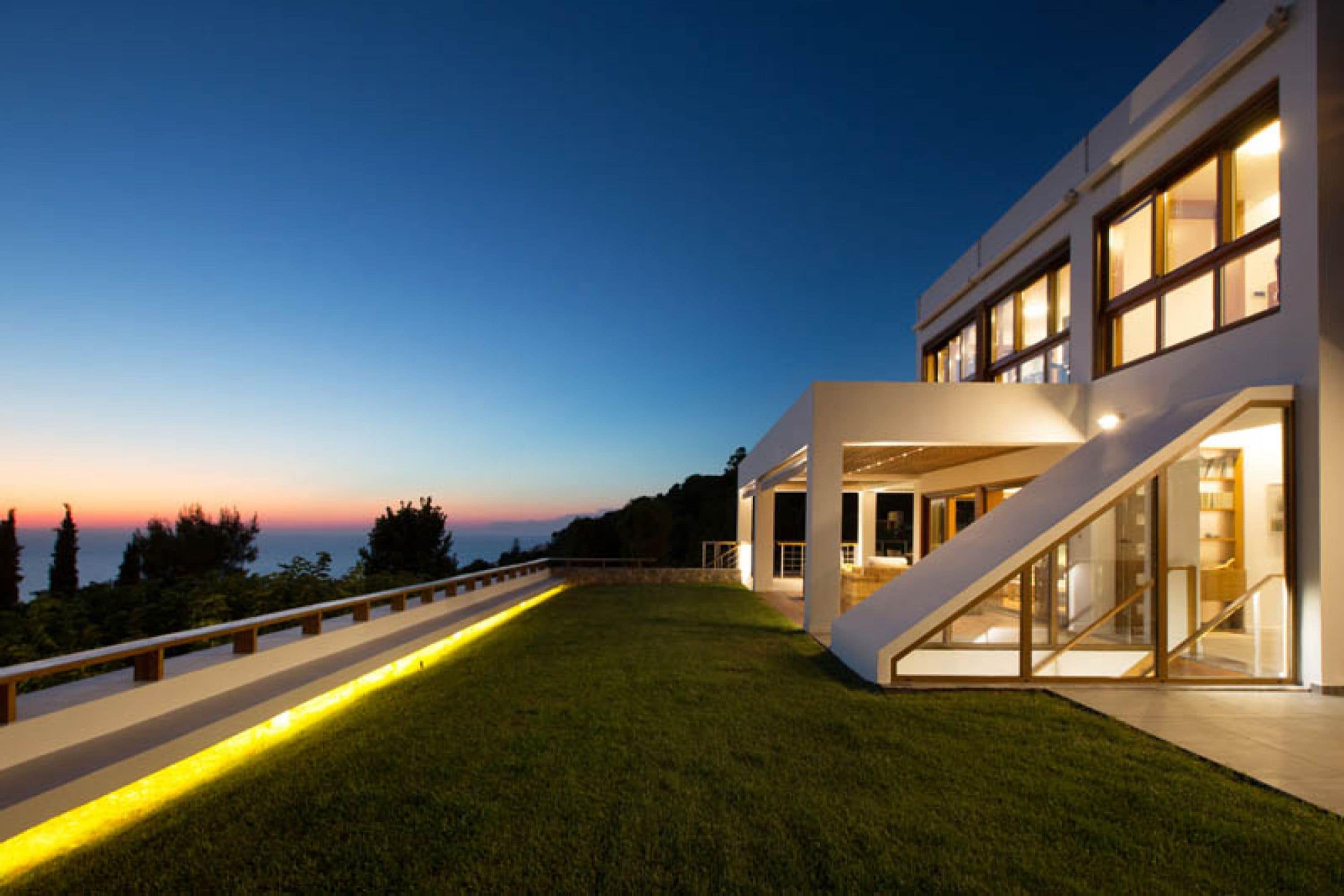 Una casa moderna con techo inclinado, ventanas amplias y un césped cuidado.