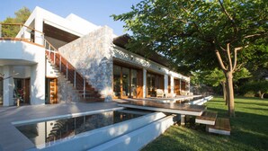 A modern house with a stone facade, a wooden staircase, and a pool area. - Villa Terra Creta Luxury Retreat and Spa (Chania)