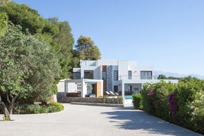 Ein modernes, zweistöckiges Gebäude mit Steinverkleidung, einem Pool und Blick auf Berge.