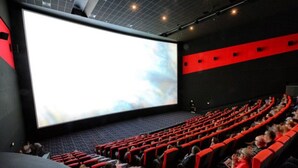 A movie theater with rows of seats, a large screen, and a dark interior.