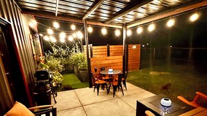 An outdoor patio with a table and chairs, string lights, and potted plants. - Farmhouse outskirts of Norman’s “Okla. University” fastWiFi, 2-75”TVs, KING BED (Noble)