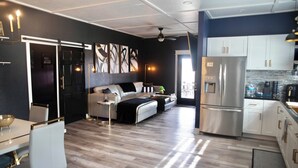 A modern kitchen with stainless steel appliances, a dining area with a white table and chairs, and a living area with a sofa and a coffee table. - Farmhouse outskirts of Norman’s “Okla. University” fastWiFi, 2-75”TVs, KING BED (Noble)