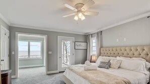 Un dormitorio con una cama grande, un ventilador de techo y vistas al exterior a través de una puerta.