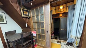 Une pièce de style japonais traditionnel, avec un tatami, une table en bois et une porte coulissante donnant accès à une salle de bain.