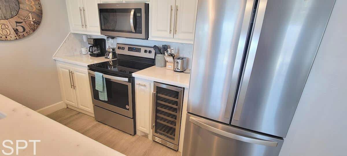 A compact kitchen with stainless steel appliances, including a microwave, oven, and refrigerator.