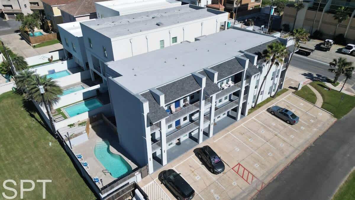 Un edificio de varios pisos con piscina en la azotea, estacionamiento y varios balcones.