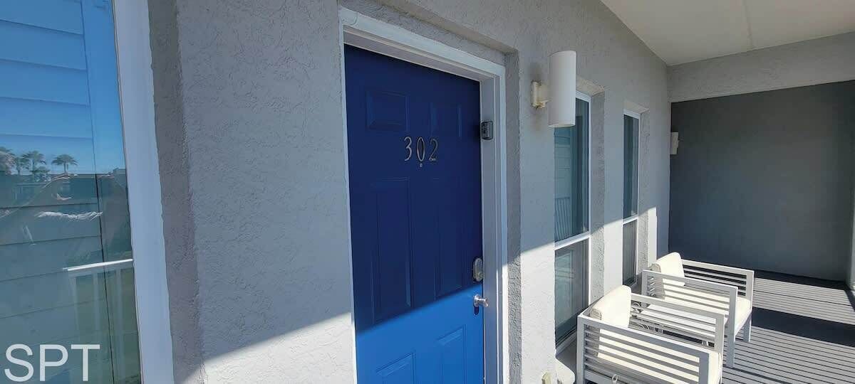A blue door with the number 302, a glass door, and a balcony with white railings.