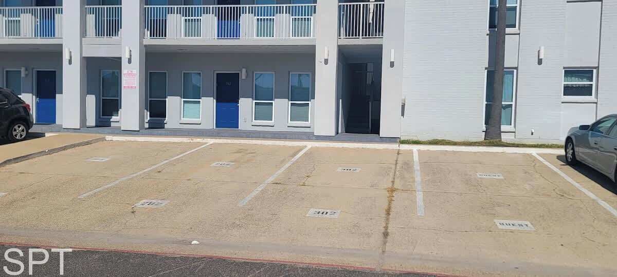 A multi-story building with a parking lot in front.