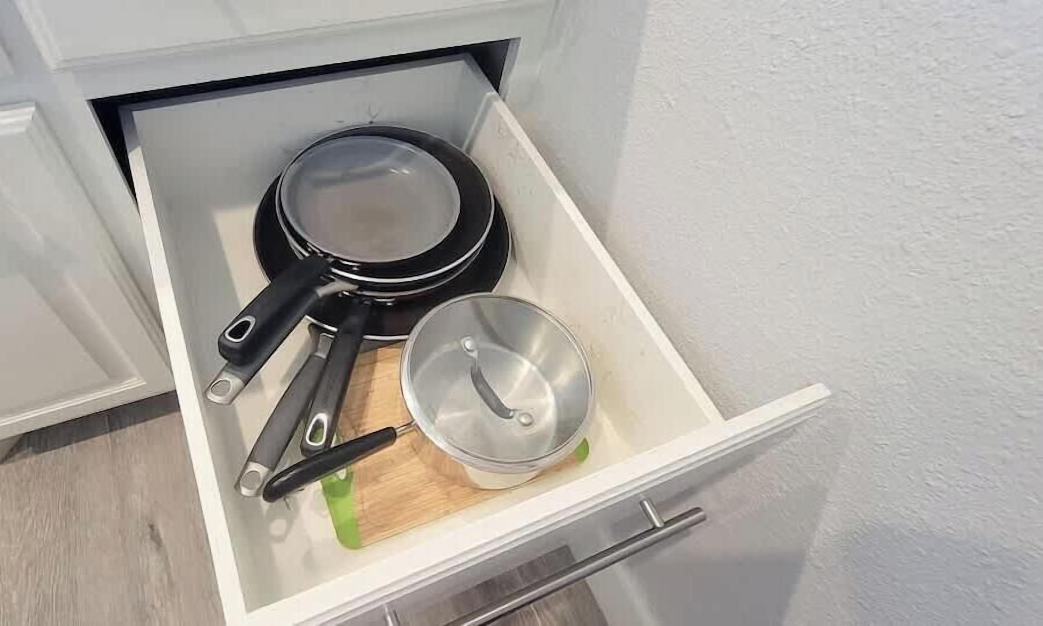 Keittiön laatikossa on paistinpannu, kattila ja puinen leikkuulauta.