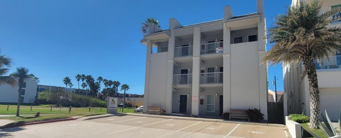 A multi-story building with a parking lot in front.