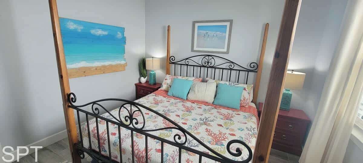 A bedroom with a bed, a nightstand, a lamp, and a painting on the wall.