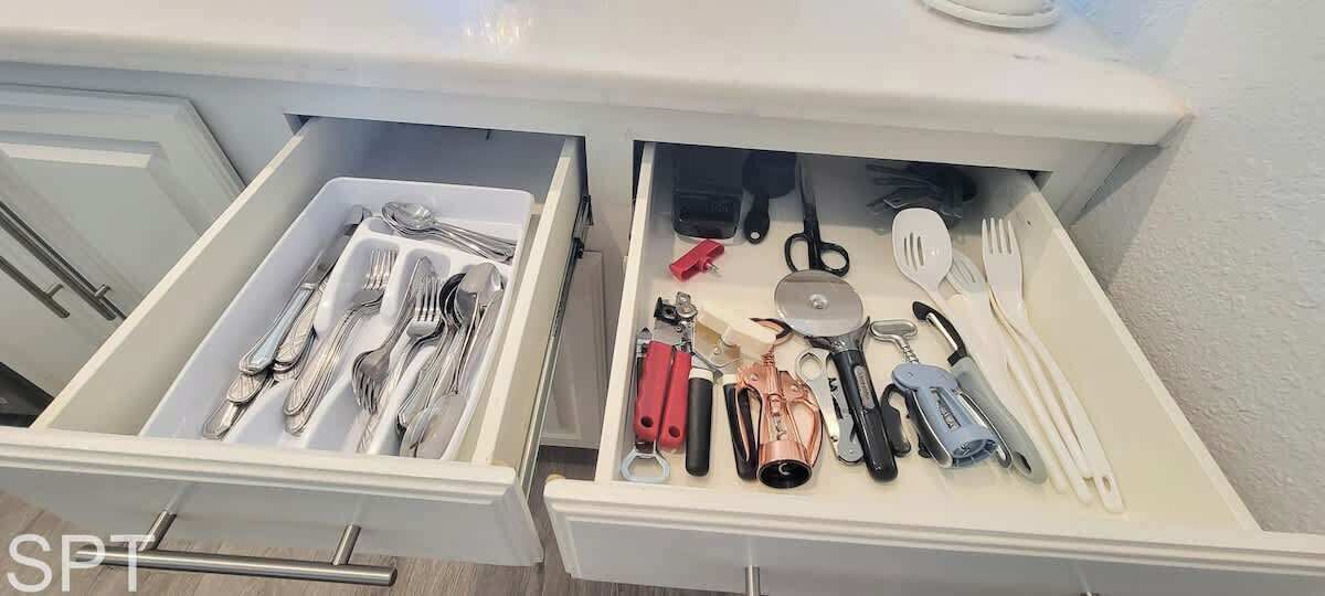 A drawer with neatly organized kitchen utensils including forks, knives, and a cutting board.