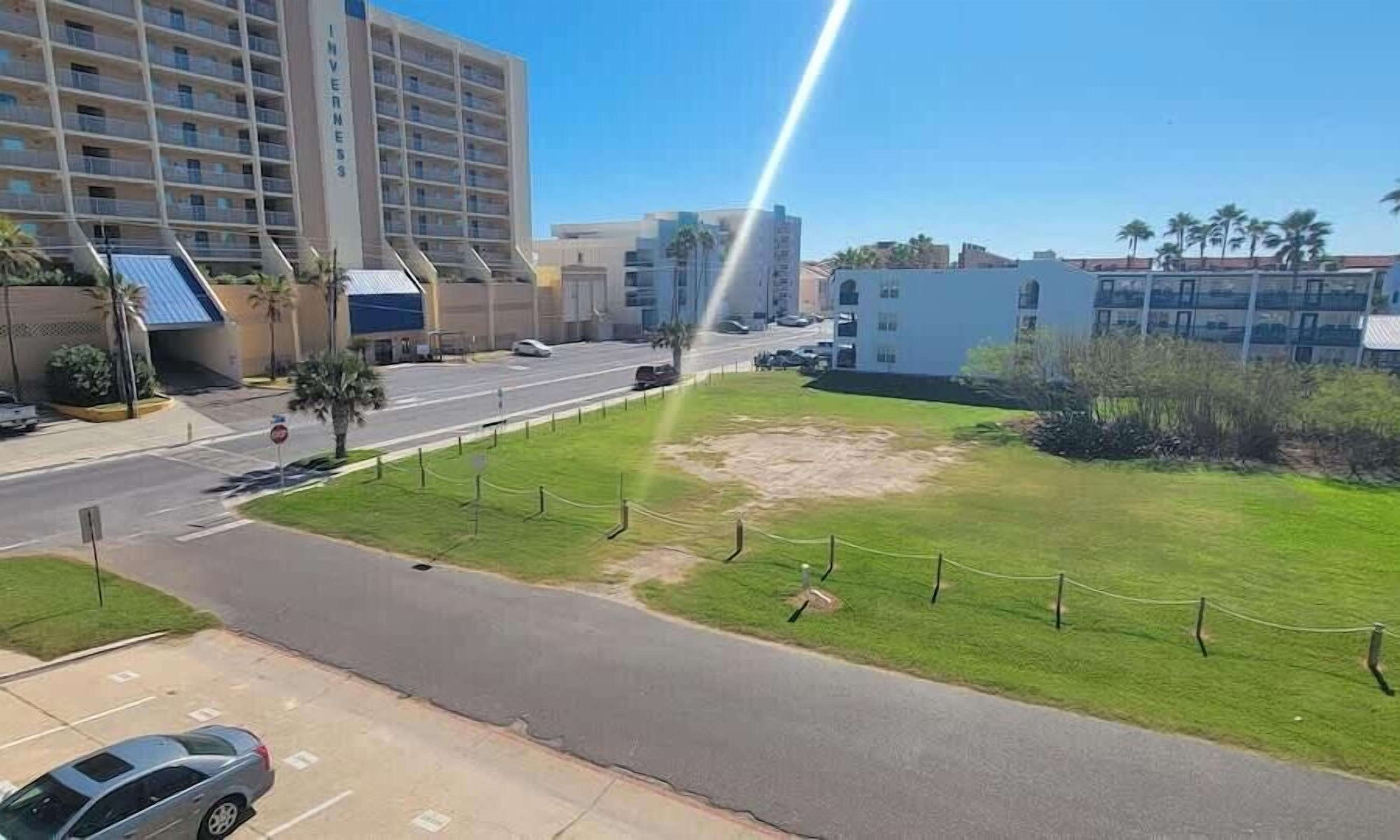 Ein Hotel mit mehreren Stockwerken, einem Parkplatz und einem Rasenstück mit Zaun.