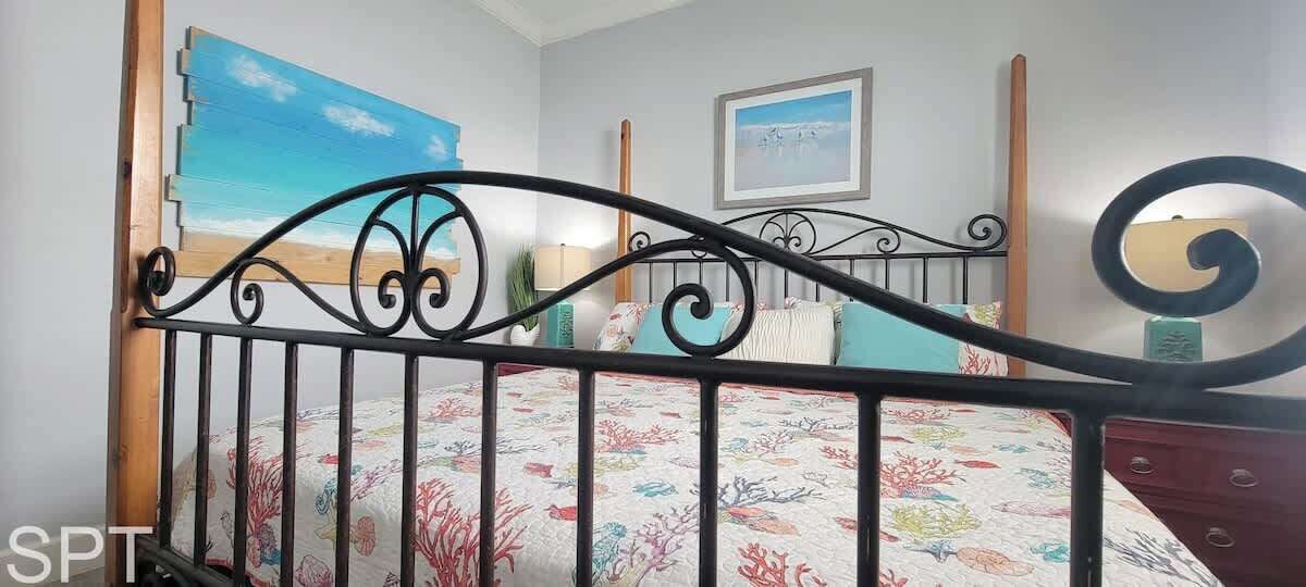 Une chambre à coucher avec un lit, un tableau, une lampe et une commode.