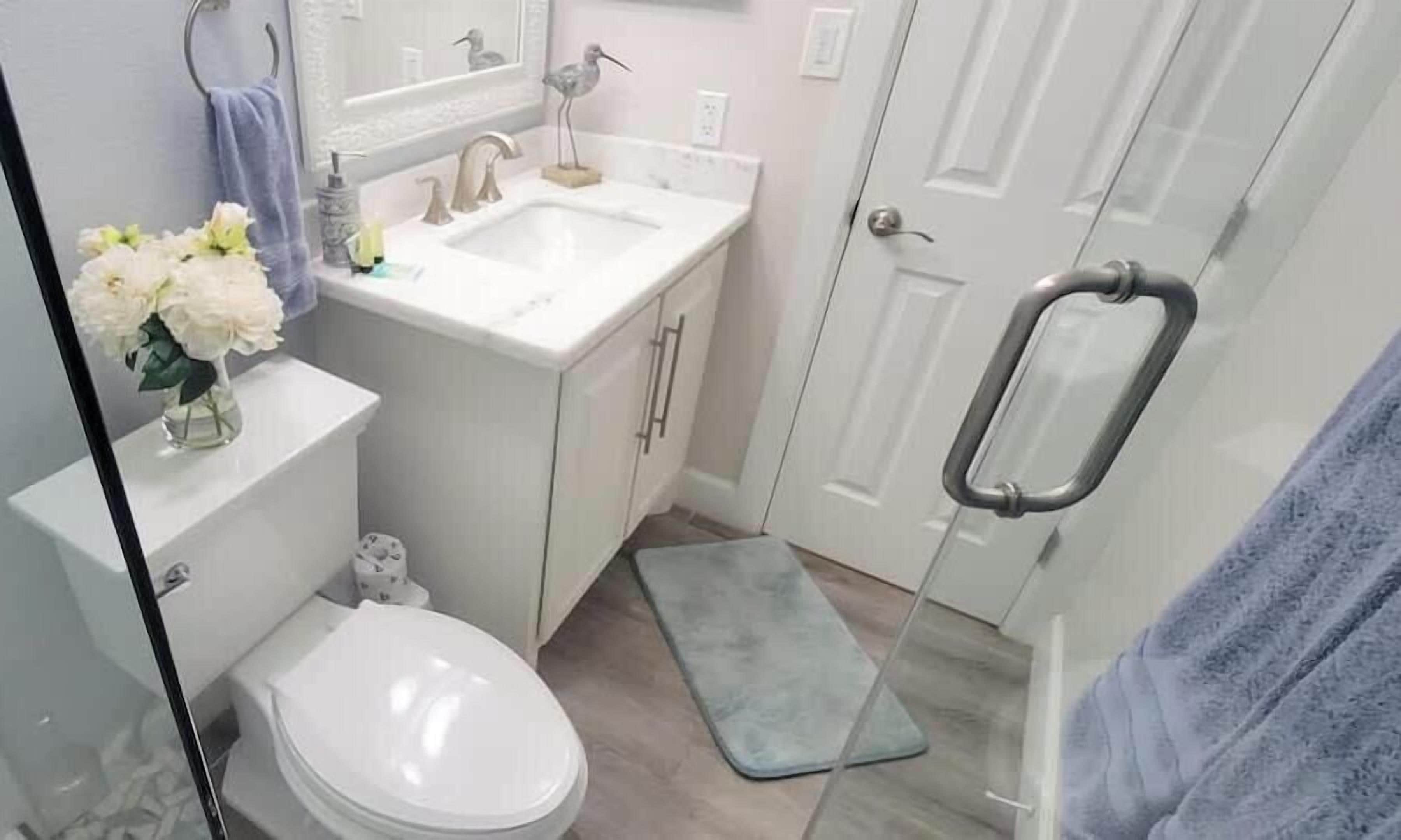 A bathroom with a toilet, sink, and shower area.