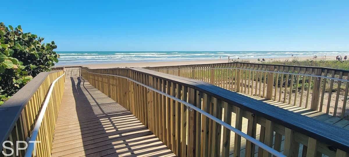 A wooden boardwalk leading to a beach with clear skies.