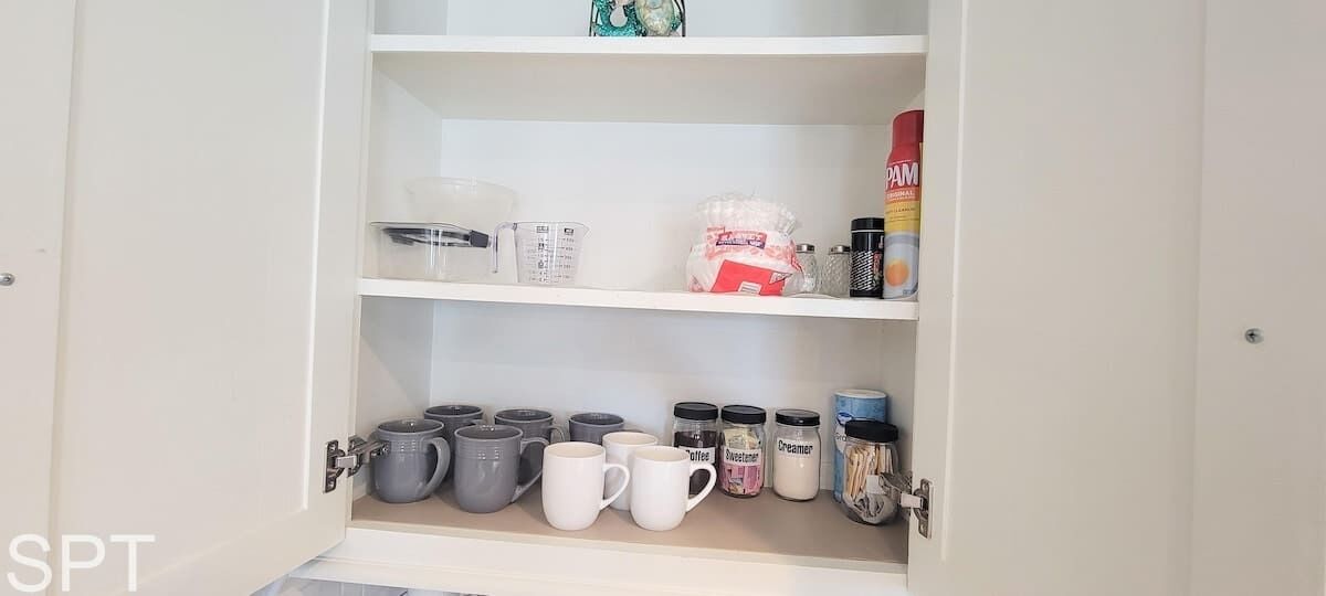 A kitchen cabinet with various kitchenware and containers.